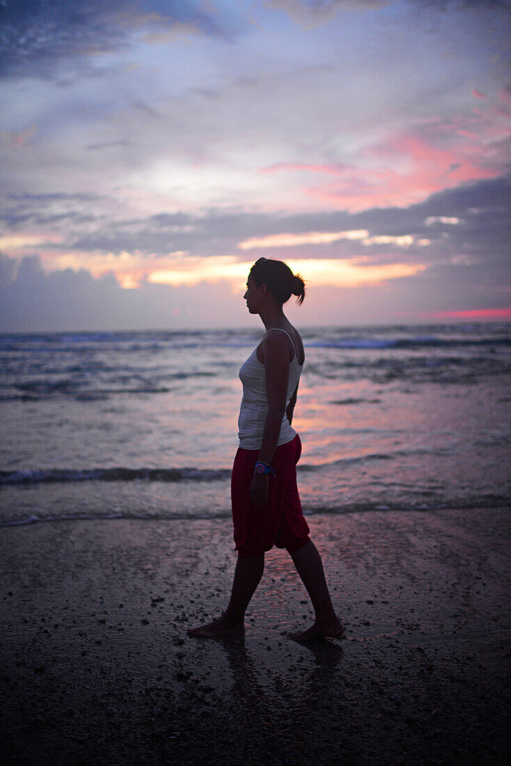 Junge Frau genießt den Sonnenuntergang am Strand von Hikkaduwa, Sri Lanka