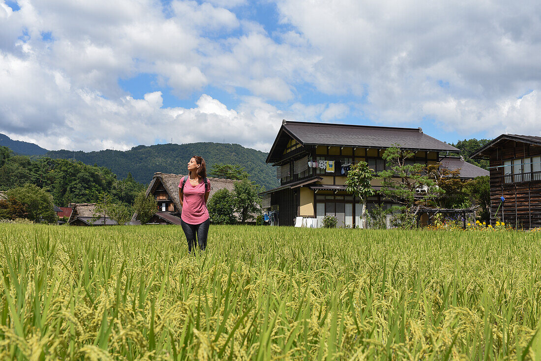 Porträt einer jungen kaukasischen Frau im Freien in Shirakawa-go, einem traditionellen Dorf, das einen als gassho-zukuri bekannten Baustil zeigt, Präfektur Gifu, Japan