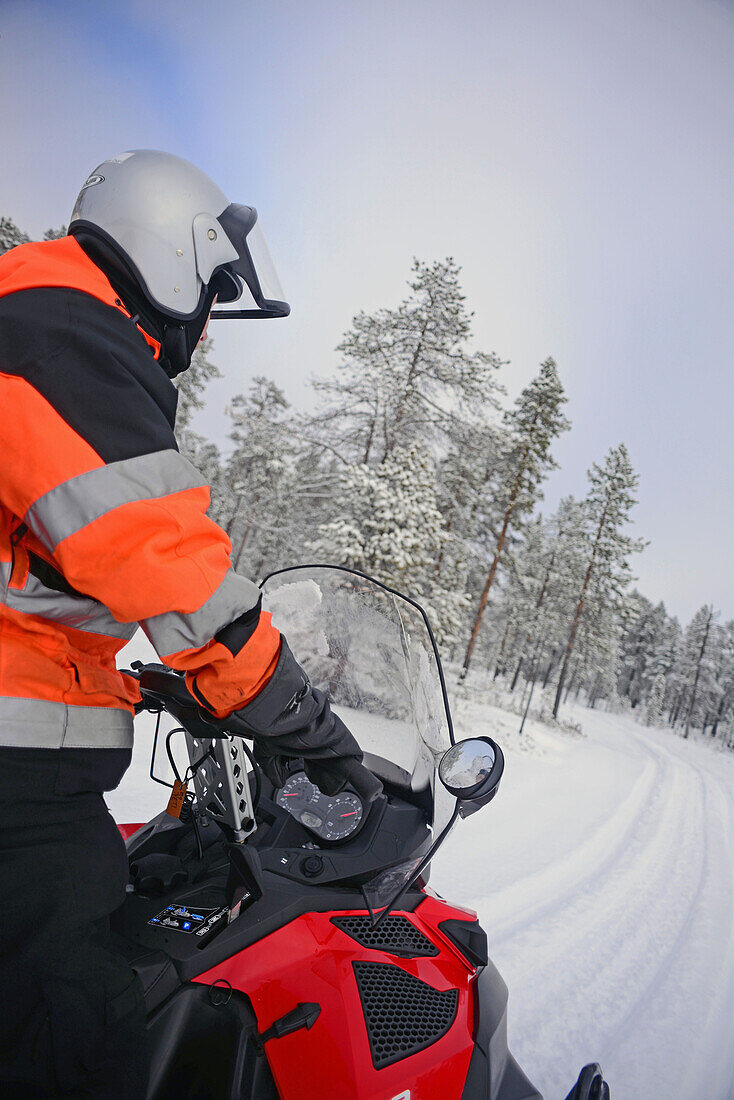 Antti, young Finnish guide from VisitInari, rides a snowmobile in the wilderness of Inari, Lapland, Finland