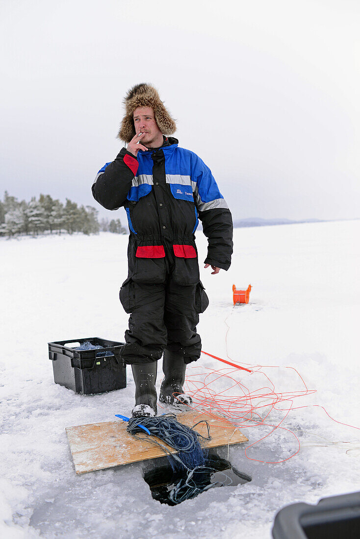 Fisherman practicing ice fishing in Lake Inari, Lapland, Finland