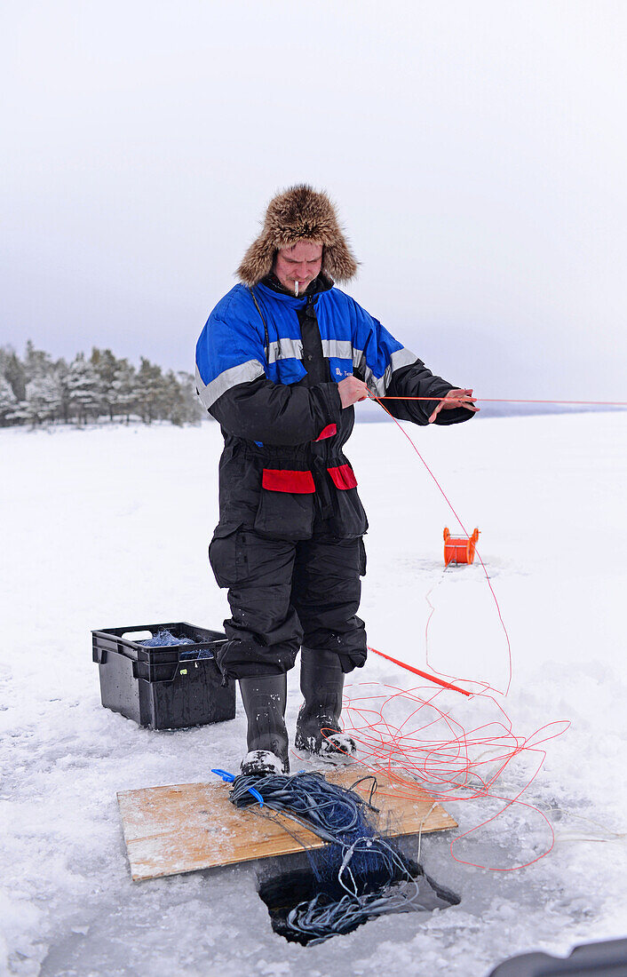 Fischer beim Eisfischen im Inari-See, Lappland, Finnland