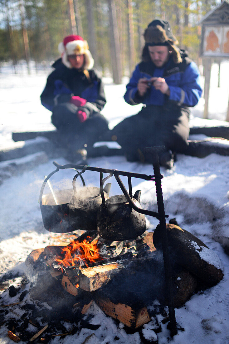 Halt für ein warmes Getränk und Essen, am Feuer. Wildnis-Husky-Schlittentour in der Taiga mit Bearhillhusky in Rovaniemi, Lappland, Finnland