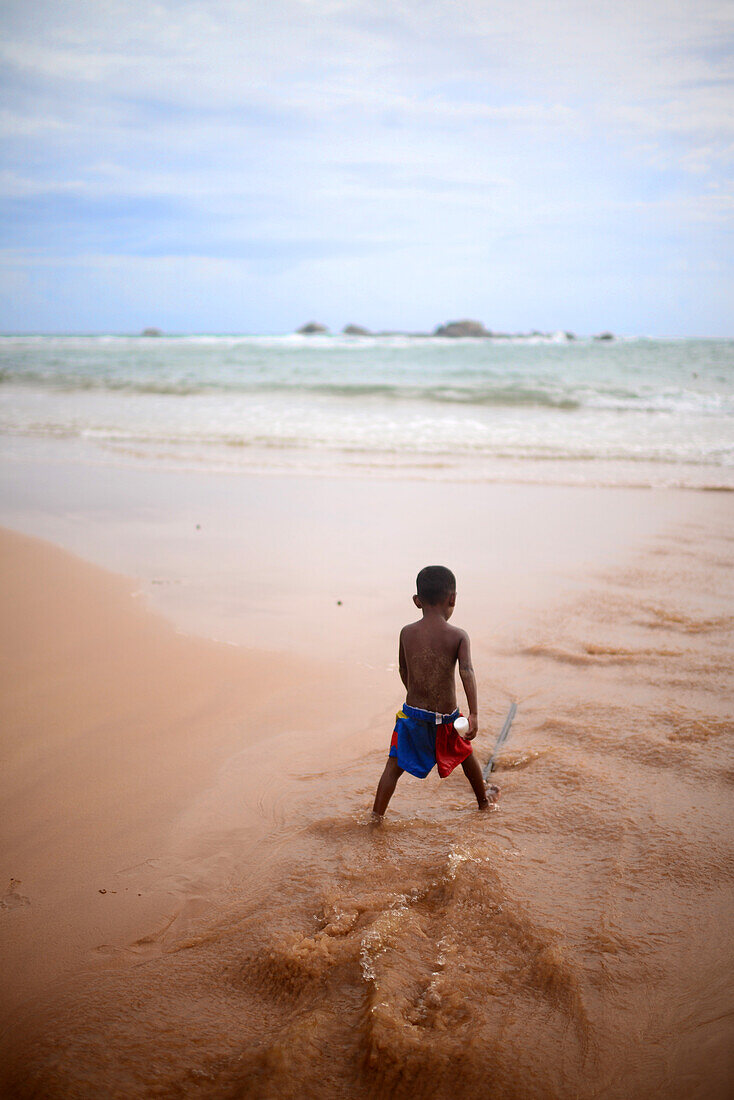 Kleiner Junge spielt am Strand, Hikkaduwa, Sri Lanka