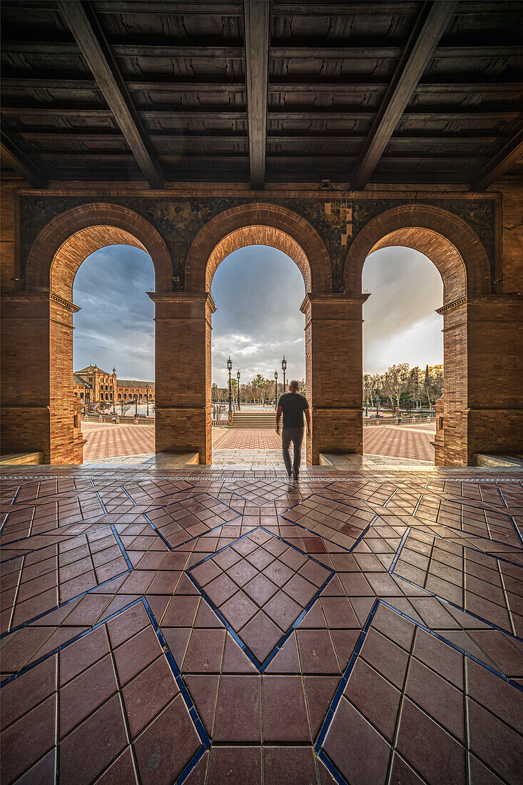 Silhouettierte Person, die durch einen bogenförmigen Korridor geht, Plaza de EspaUa, Sevilla, Spanien