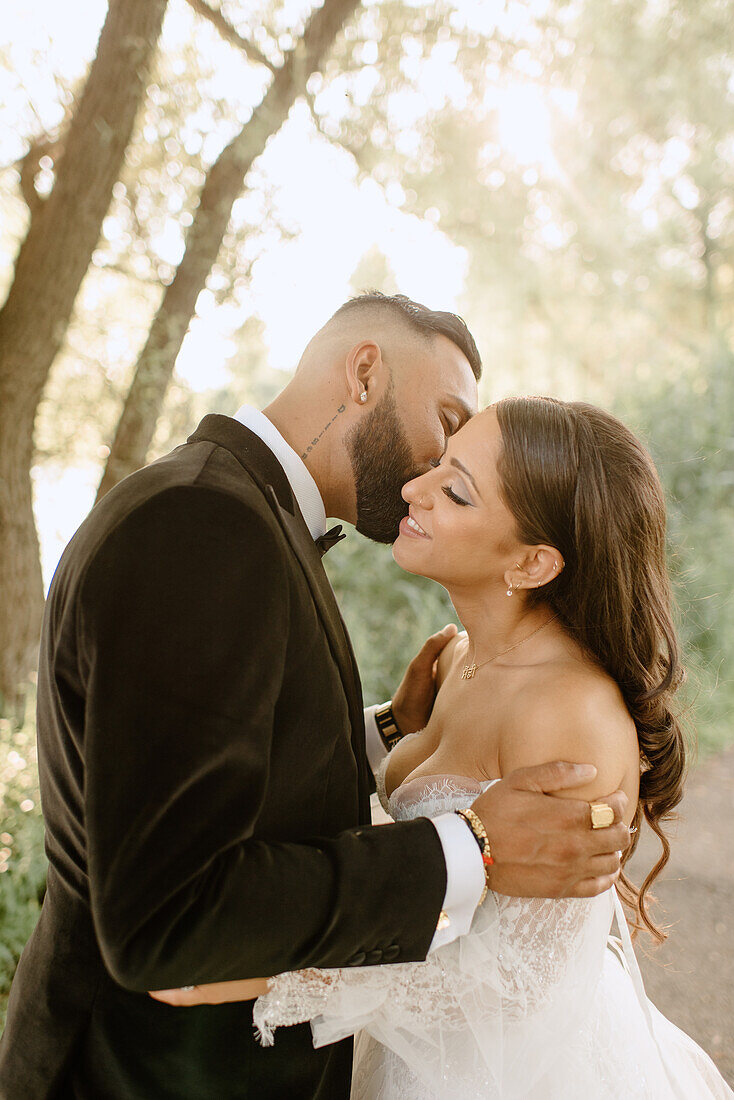 Bride and groom kissing in park