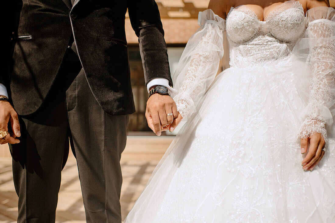 Mittelteil von Braut und Bräutigam beim Händchenhalten