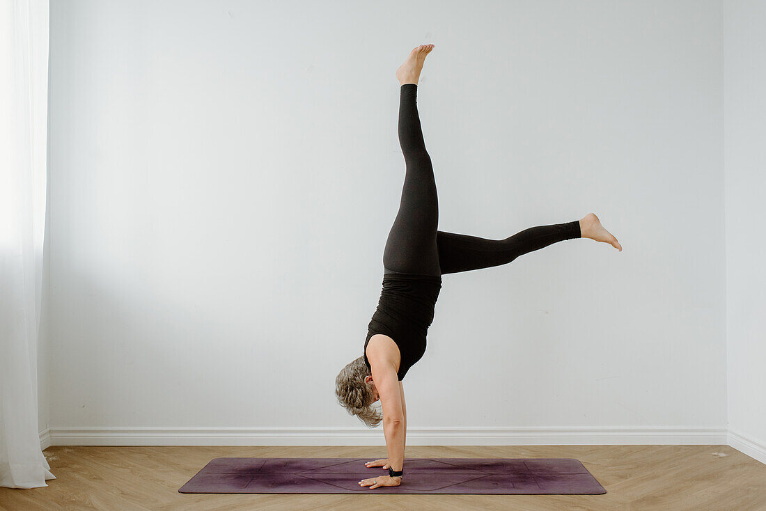 Studio shot of woman performing handstand