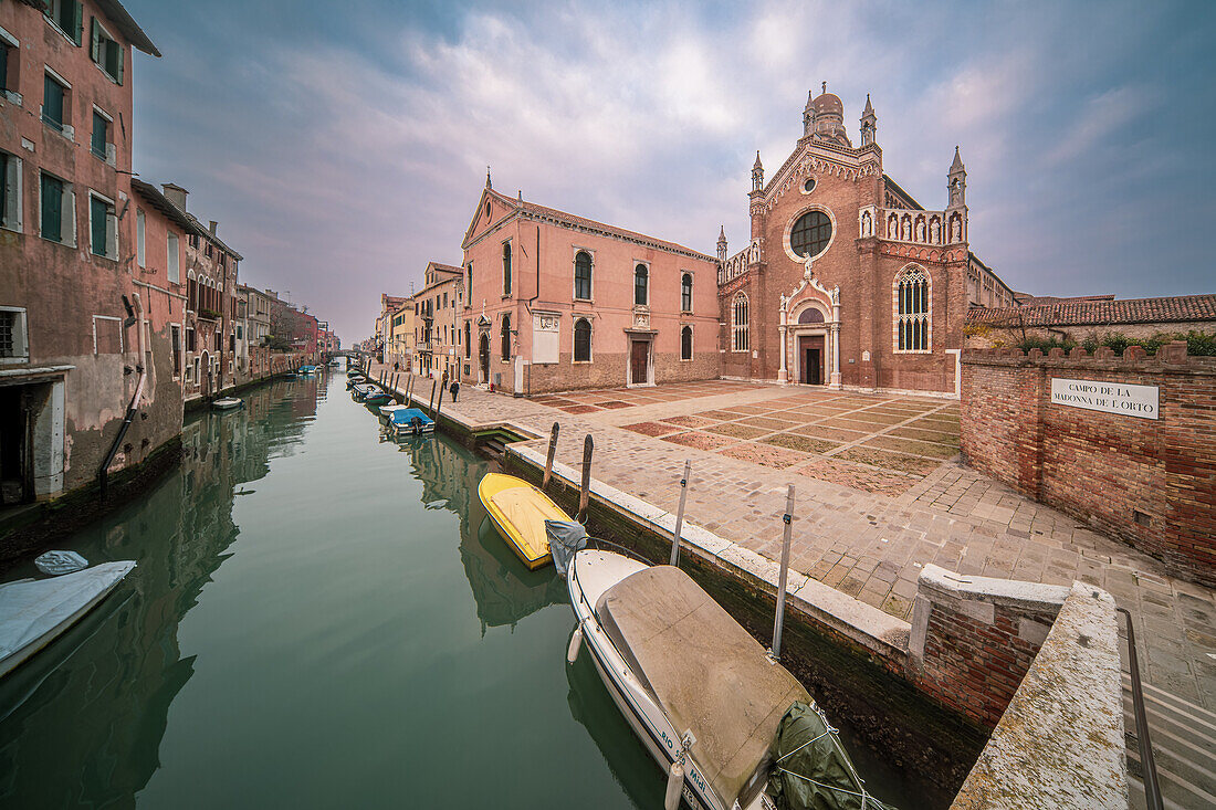 Ein heiterer Morgen in der Kirche Madonna dellíOrto im Herzen von Cannaregio, Venedig, mit ruhigem Wasser, in dem sich das architektonische Wunderwerk spiegelt