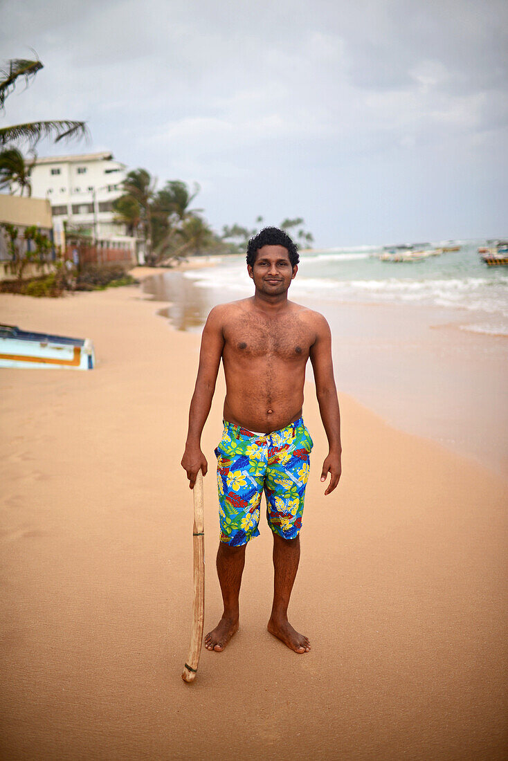 Porträt eines jungen Mannes mit einem Kricketschläger am Strand, Hikkaduwa, Sri Lanka