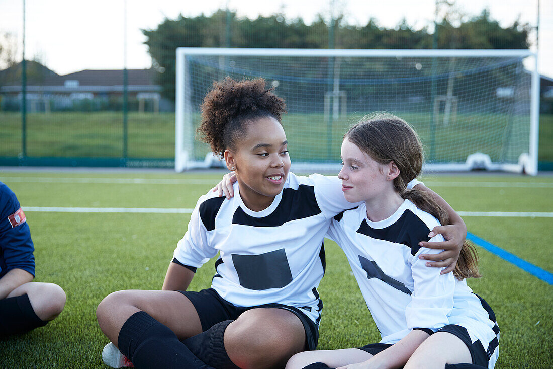 UK, Female soccer team members (12-13) embracing in field