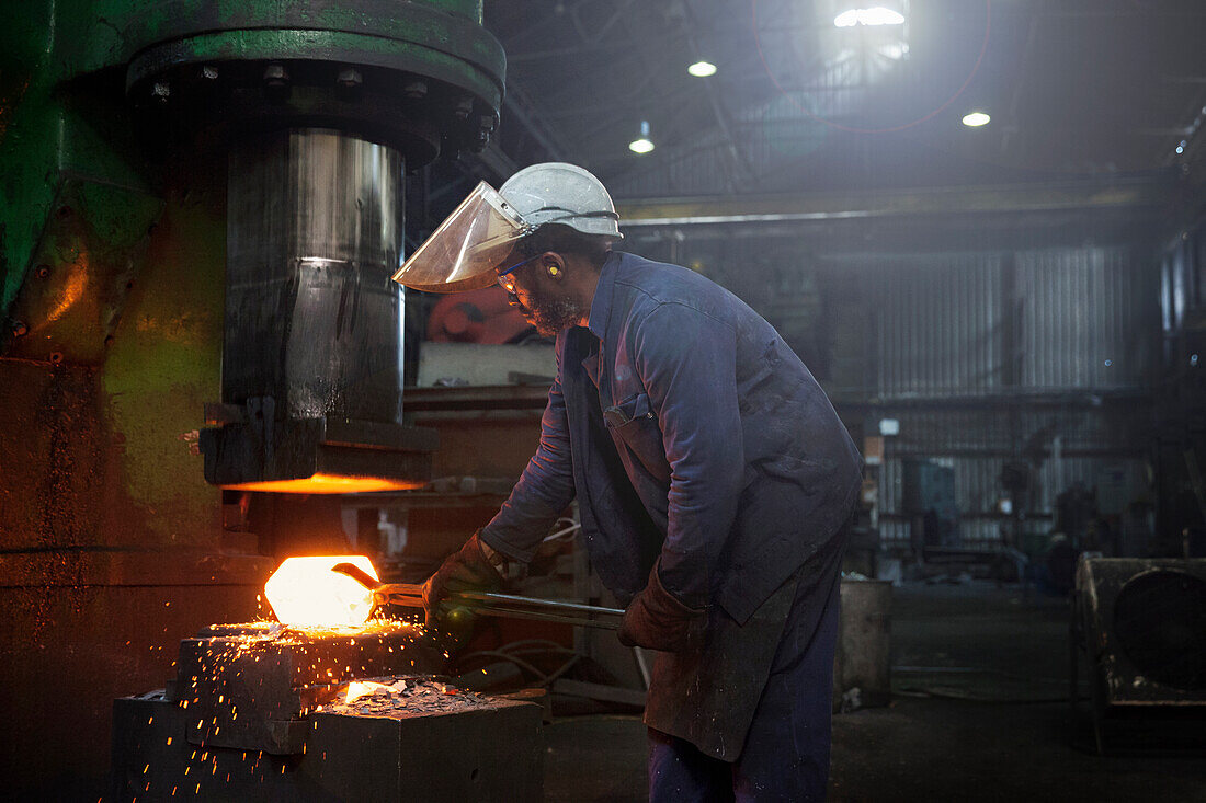 Ein Schmiedearbeiter formt einen Stahlknüppel auf einem 5-Tonnen-Hammer vor, bevor er zu einem Satz von zwei Gesenken geführt wird, um im Hammer vollständig geschmiedet zu werden