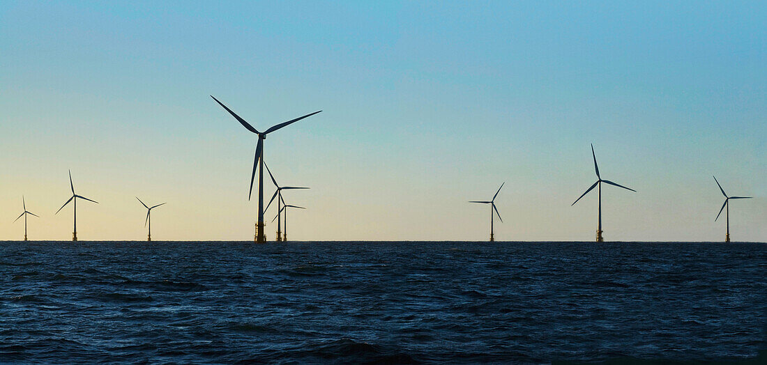 Wind turbines in water against blue sky