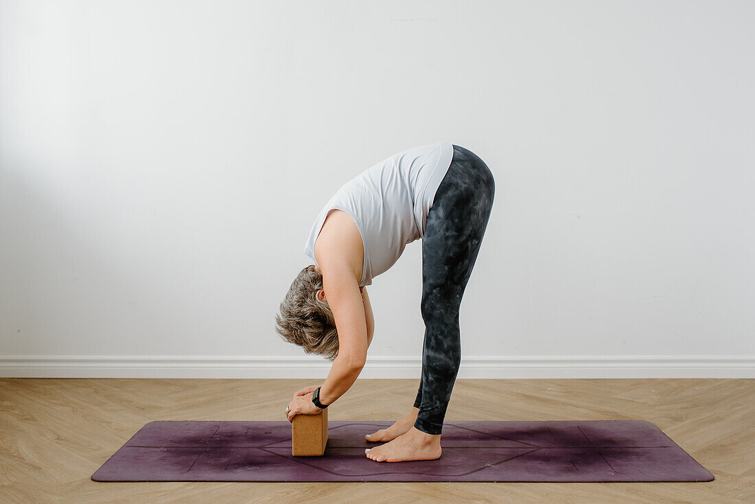 Frau übt Yoga mit Yogablock auf einer Übungsmatte