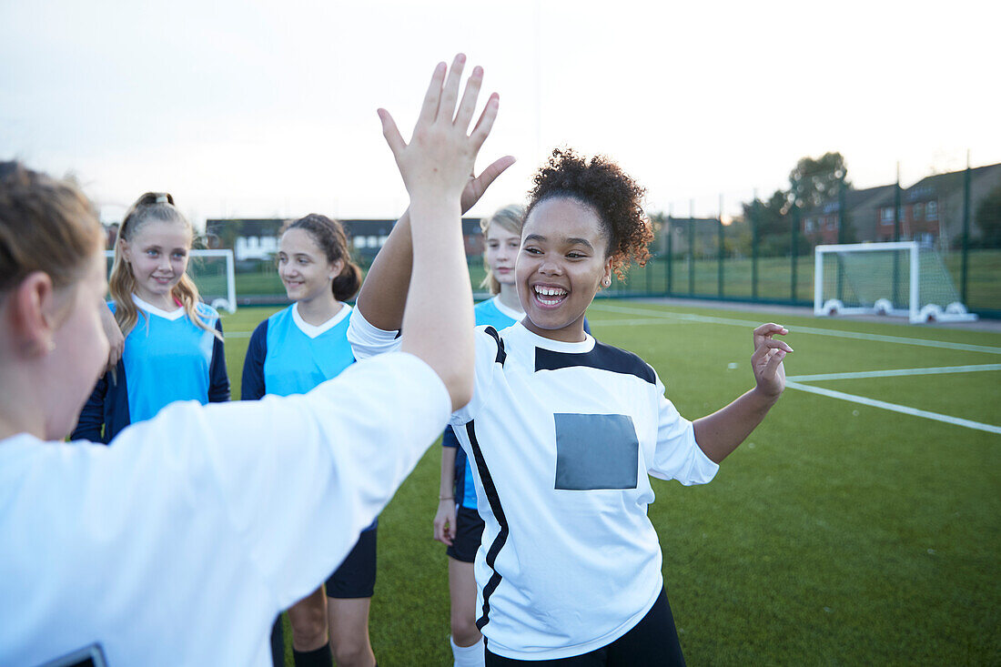 UK, Weibliche Fußballspielerinnen (10-11, 12-13) geben High Five auf dem Feld