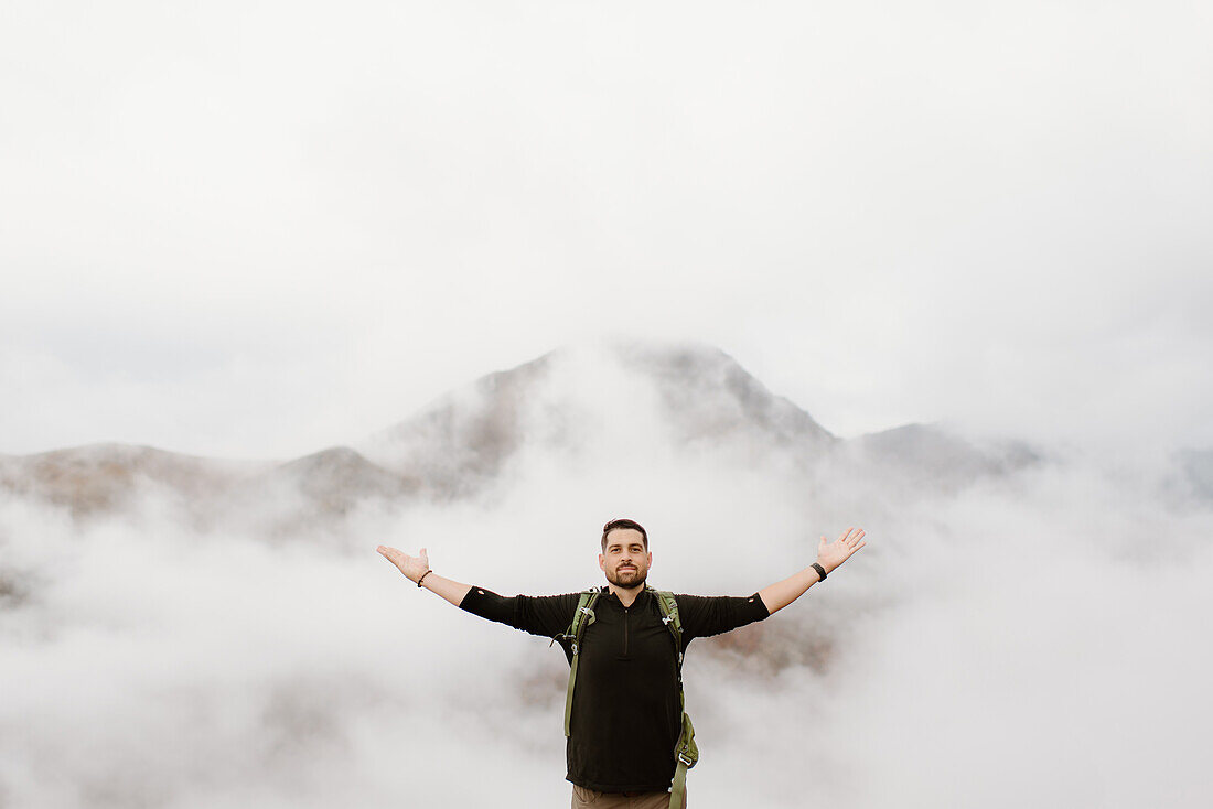 Canada, Whitehorse, Portrait of man with arms raised in foggy landscape