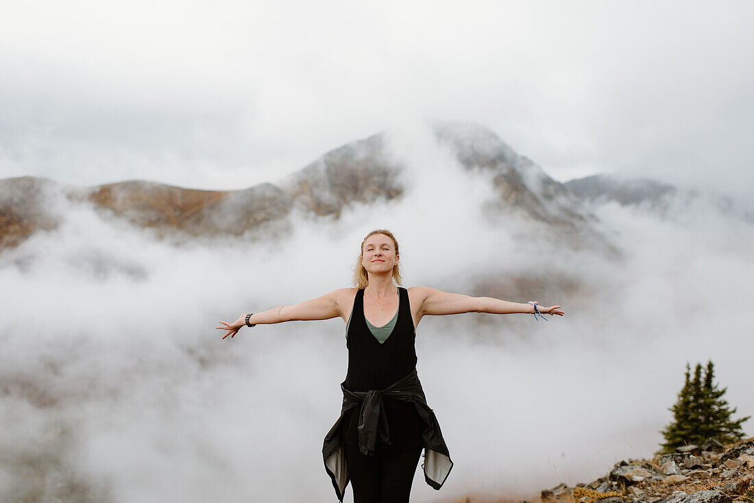 Canada, Whitehorse, Portrait of woman with arms outstretched in foggy landscape