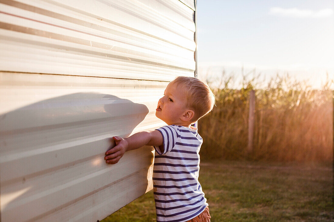 Boy (18-23 months) outside caravan in field