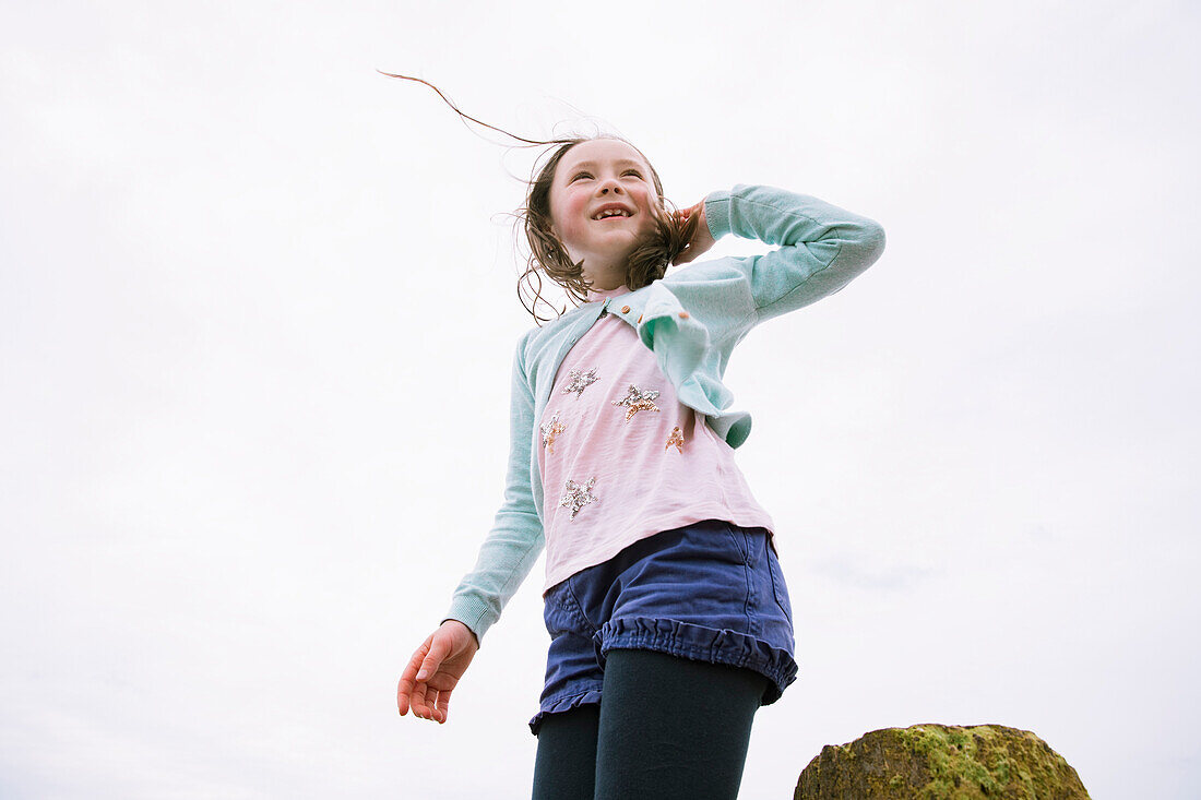 Low angle view of smiling girl (4-5) against sky