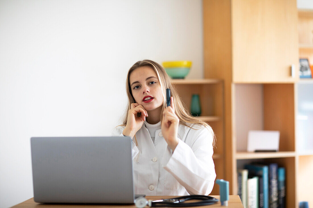 Portrait of young female doctor with laptop