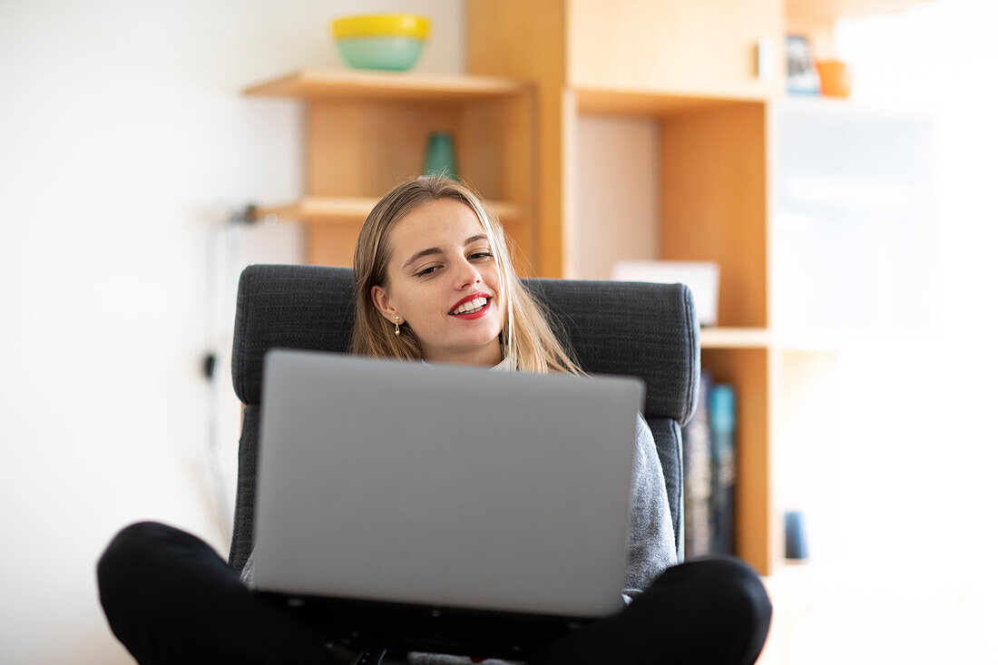 Smiling young woman using laptop at home