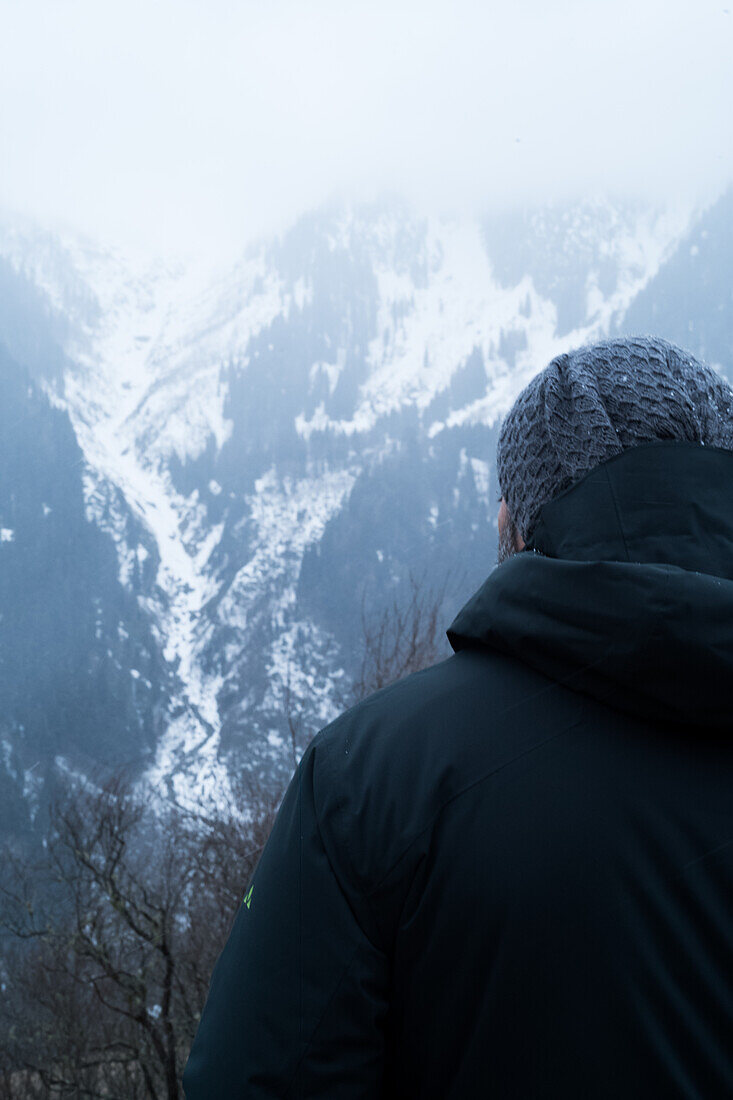 Türkei, Rückansicht eines Mannes mit Blick auf einen mit Schnee und Nebel bedeckten Berg