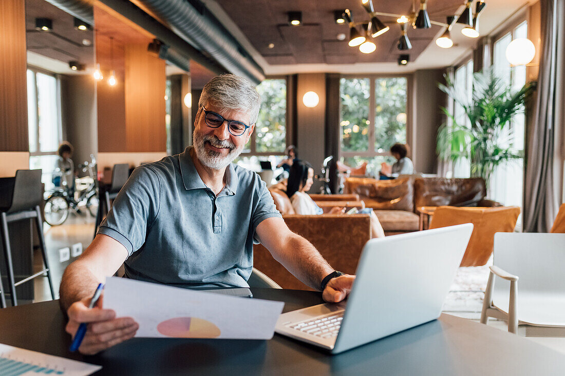 Italy, Smiling man working at table in creative studio