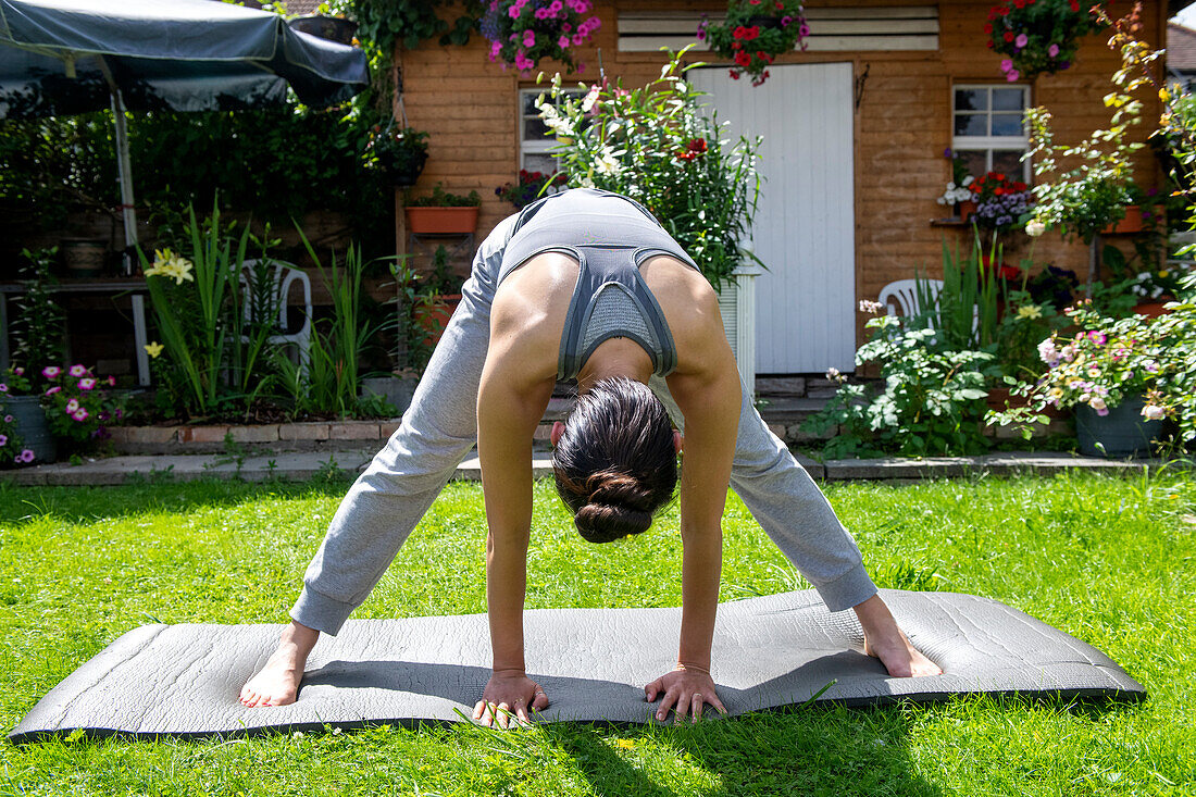 UK, London, Frau macht Yoga auf dem Rasen vor dem Haus