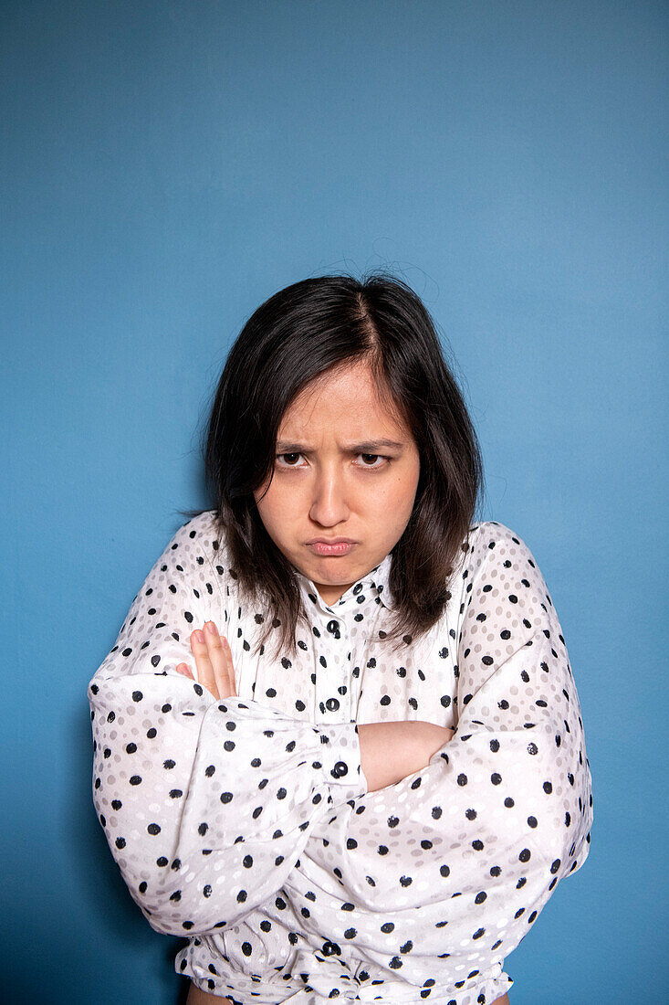 Studio-Porträt einer wütenden Frau vor blauem Hintergrund