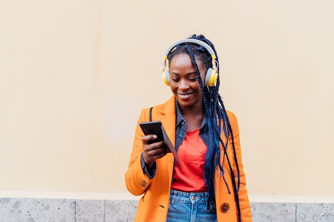 Italy, Milan, Woman with headphones and smart phone outdoors