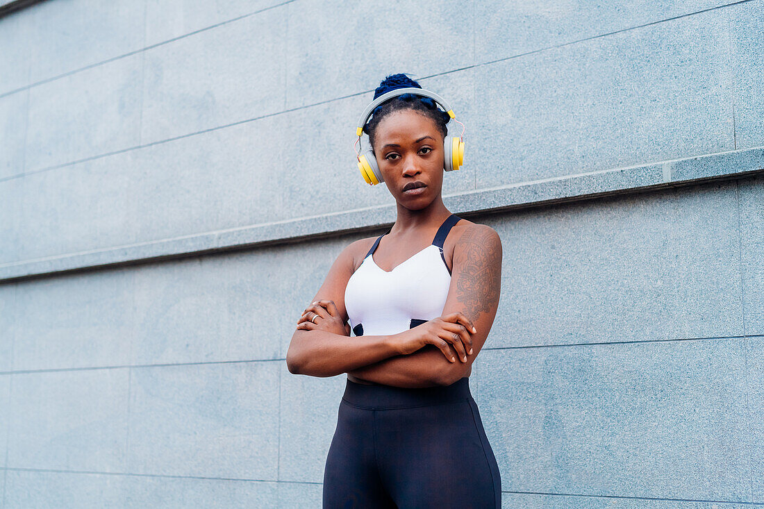 Italy, Milan, Portrait of woman in sports bra and headphones in city