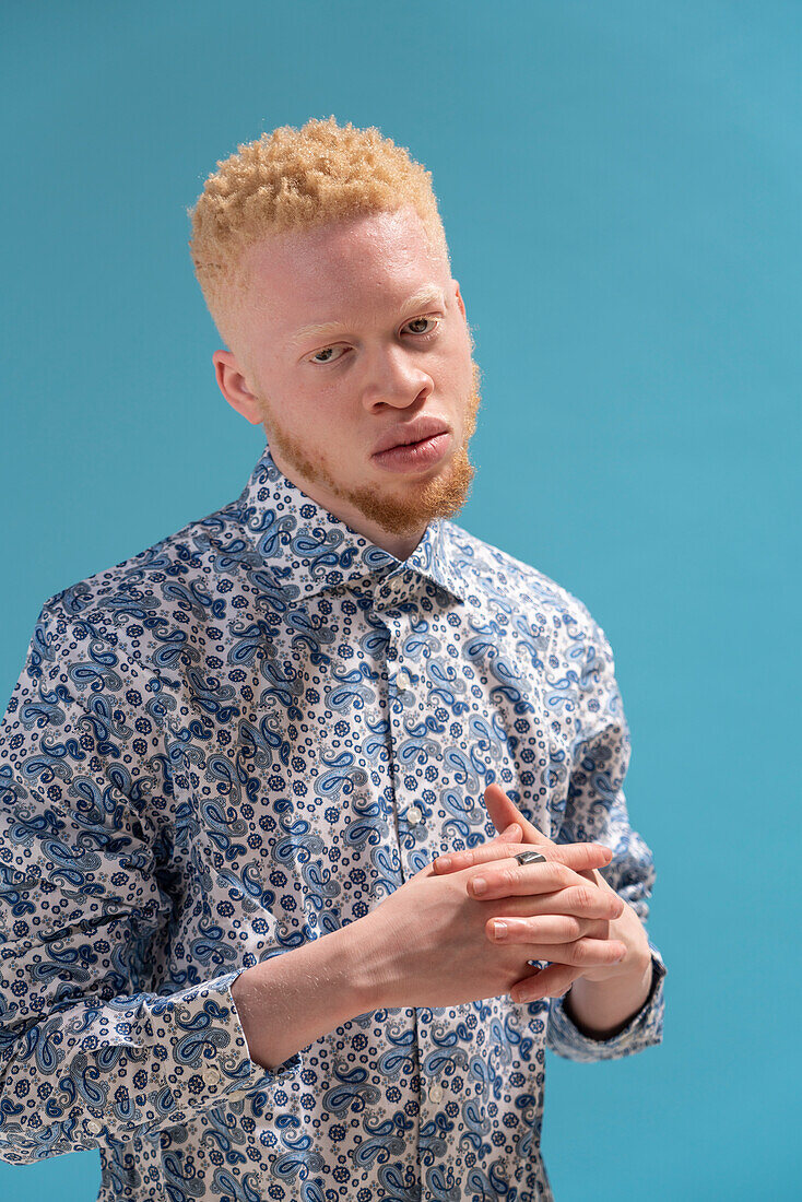 Studio-Porträt eines Albino-Mannes in blau gemustertem Hemd