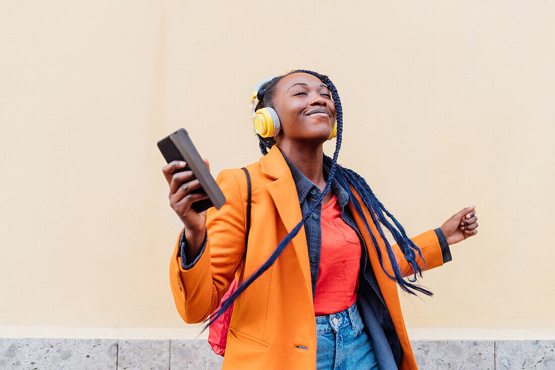 Italy, Milan, Woman with headphones and smart phone dancing outdoors