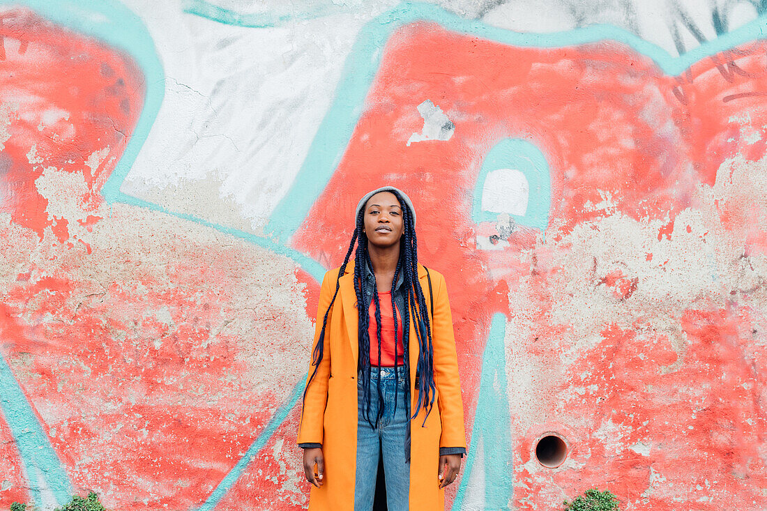 Italy, Milan, Portrait of woman with braids against graffiti covered wall