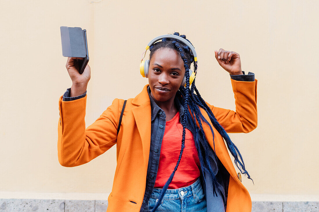 Italy, Milan, Woman with headphones and smart phone dancing outdoors