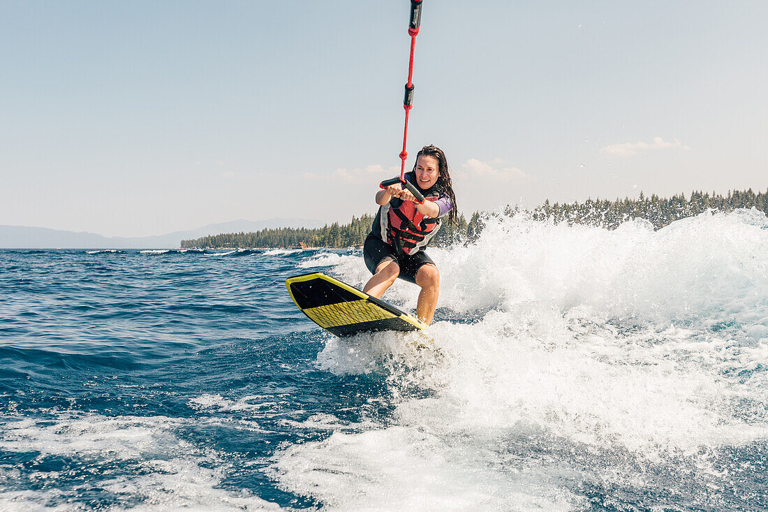 Frau beim Wakeboarden auf dem See