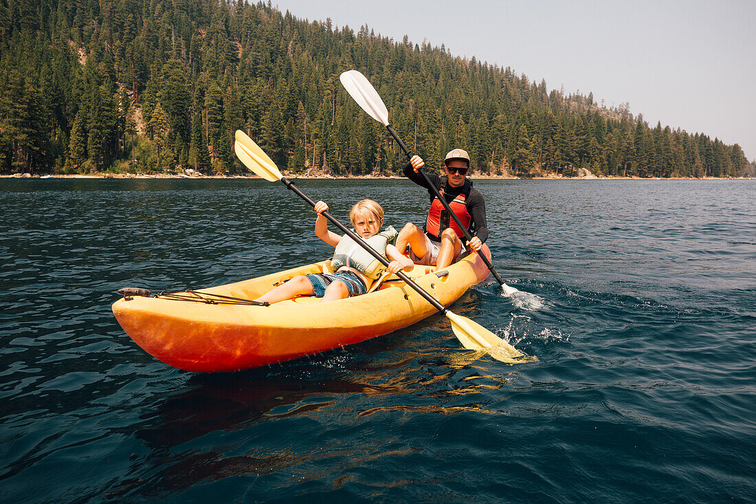 Father with son (7-8) in kayak at lake