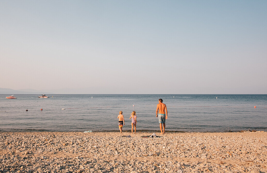 Vater mit Kindern (6-7, 8-9) am Strand