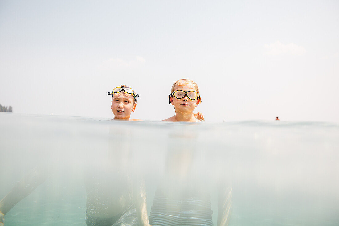 Boys (8-9) in swimming goggles in lake