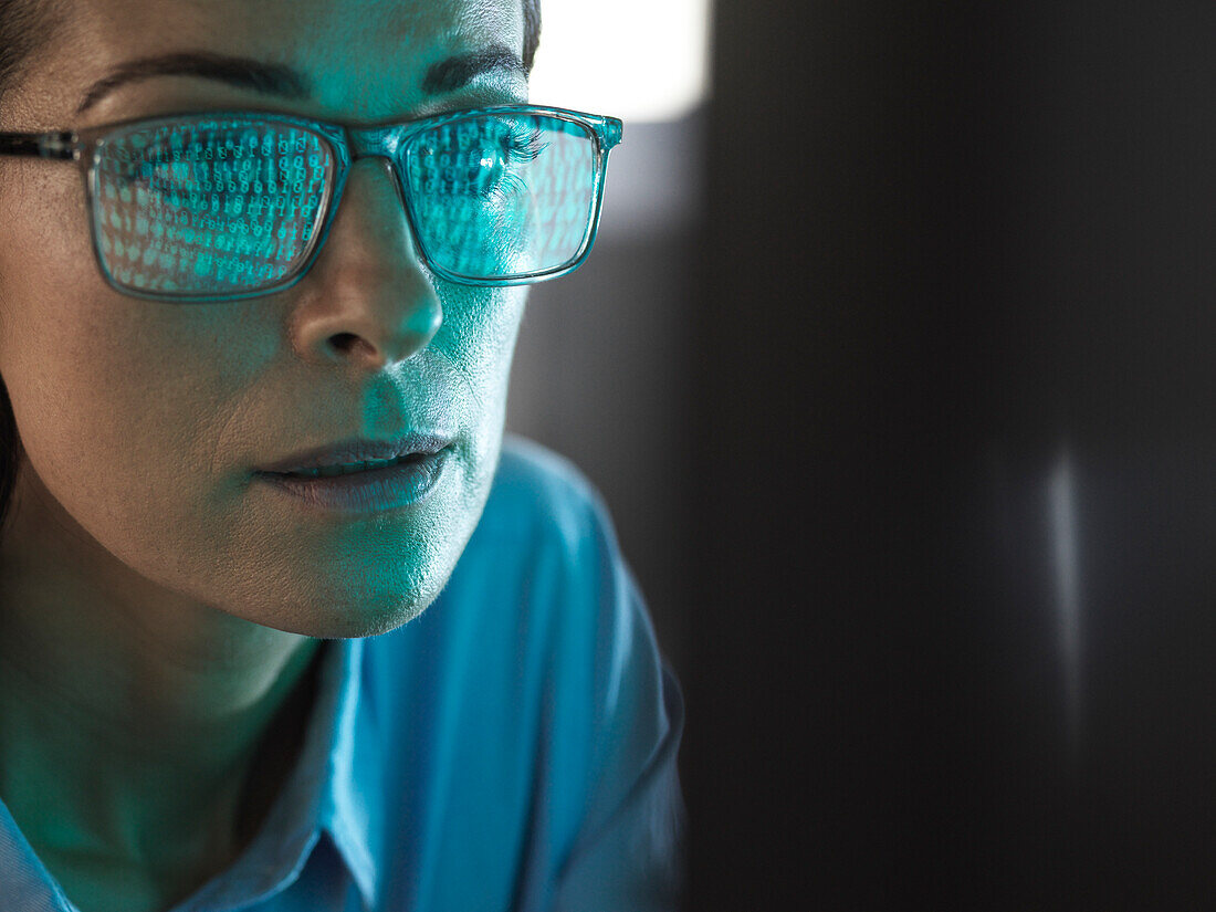 Close-up of programmer with binary code reflected in eyeglasses