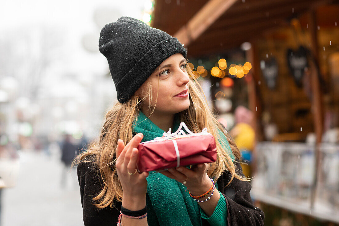 Junge Frau mit Weihnachtsgeschenk in der Hand im Freien