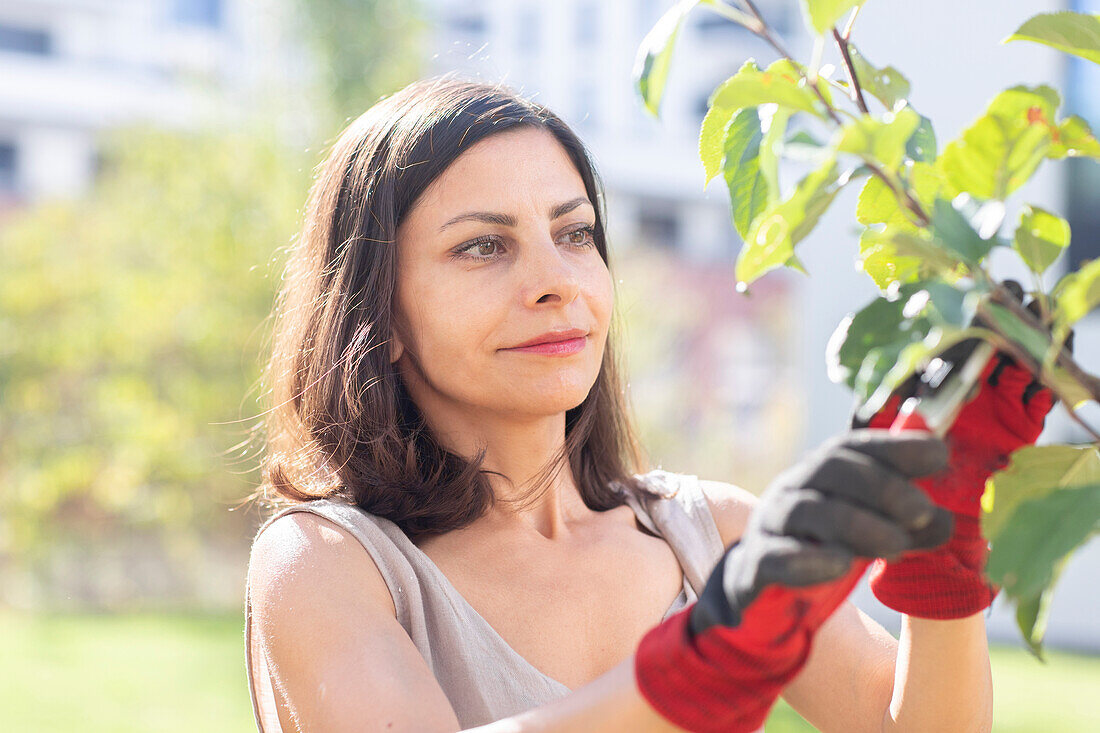 Frau beschneidet Baum im Garten