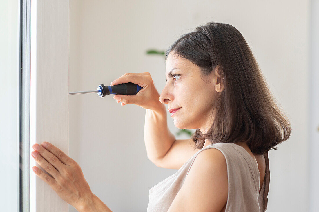 Woman using screwdriver at home