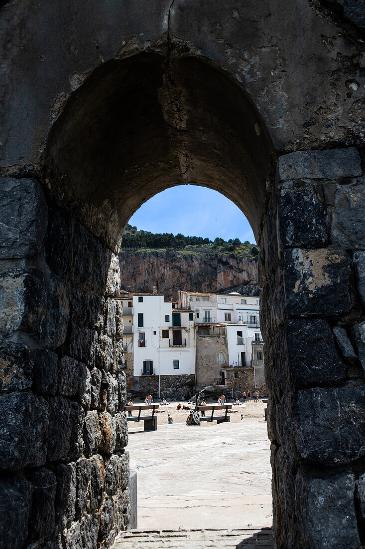 Old town square seen through stone arch, Sicily, Italy