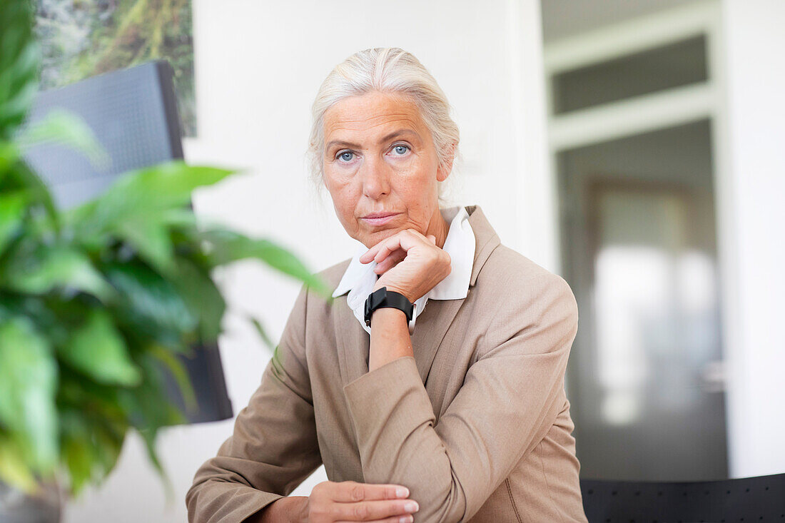 Porträt einer reifen Geschäftsfrau, die am Schreibtisch im Büro sitzt