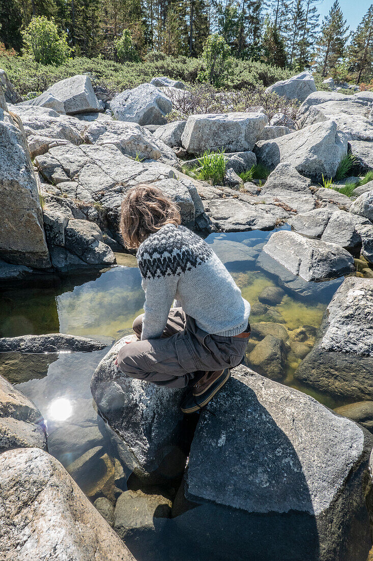 Boy (14-15) playing on rocks by lake