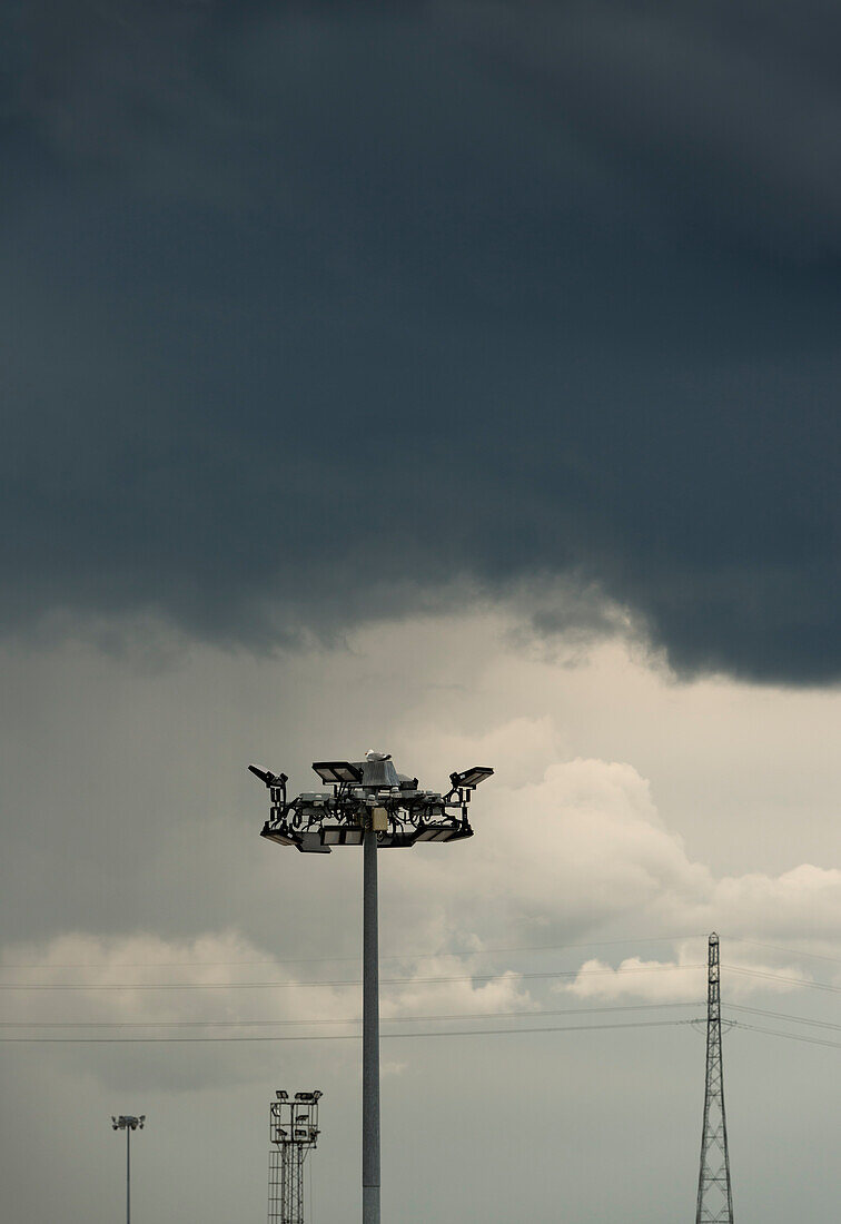 Floodlights against storm clouds on sky