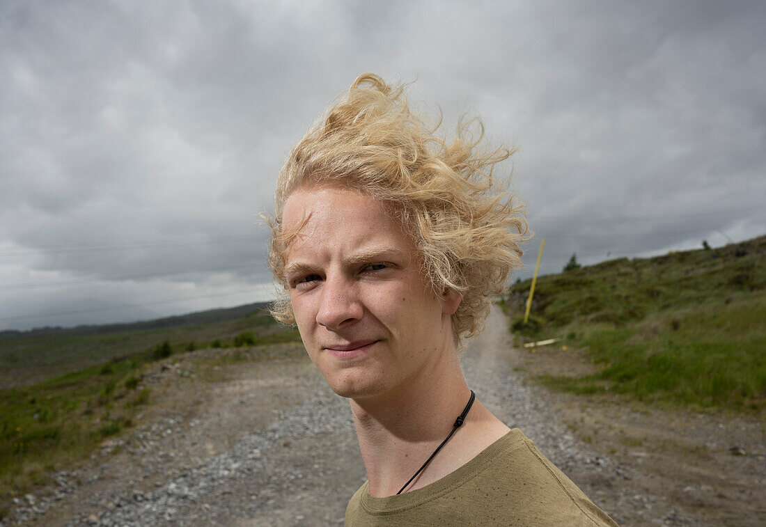 UK, Scotland, Portrait of young blonde man in landscape on windy day