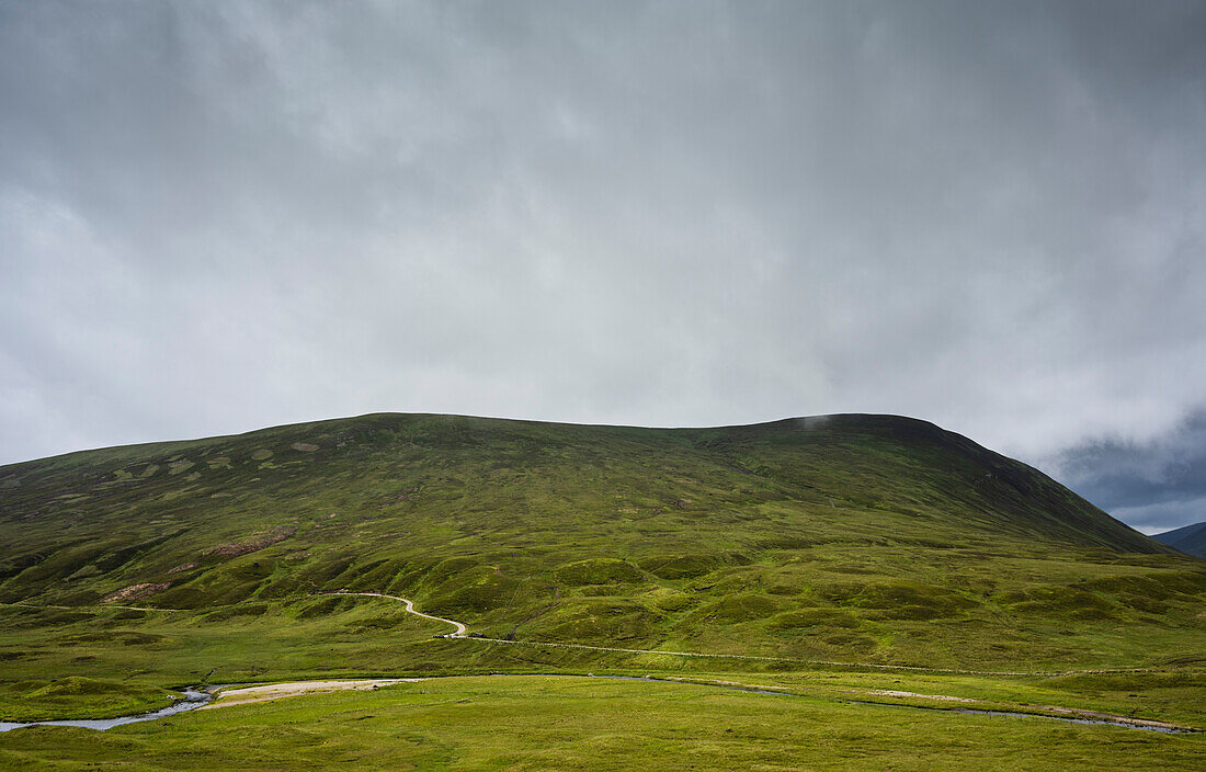 UK, Scotland, Storm clouds above green hill