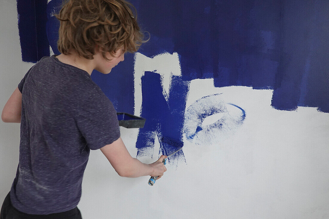 Junge bemalt Wand mit blauer Farbe