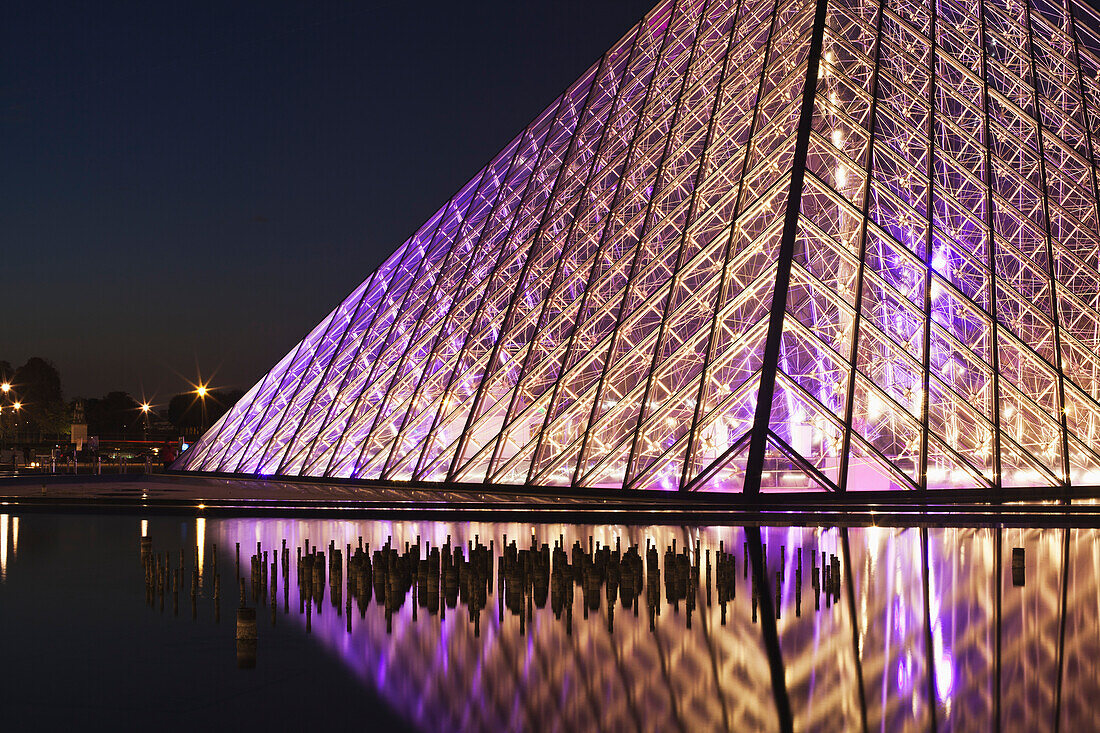 Die beleuchtete Glaspyramide des Louvre-Museums am Rande des Wassers bei Nacht; Paris, Frankreich